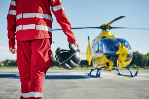 secouriste  avec uniforme rouge allant vers hélicoptère jaune