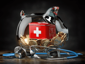 Tirelire transparente avec pièces de monnaie et boîte rouge avec symbole suisse à l'intérieur. Un stéthoscope bleu à l'extérieur