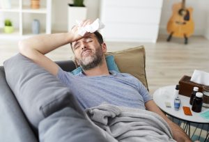 Homme malade couché sur un canapé.