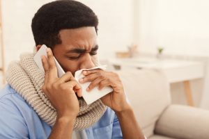 Jeune homme qui se mouche faisant un appel téléphonique.