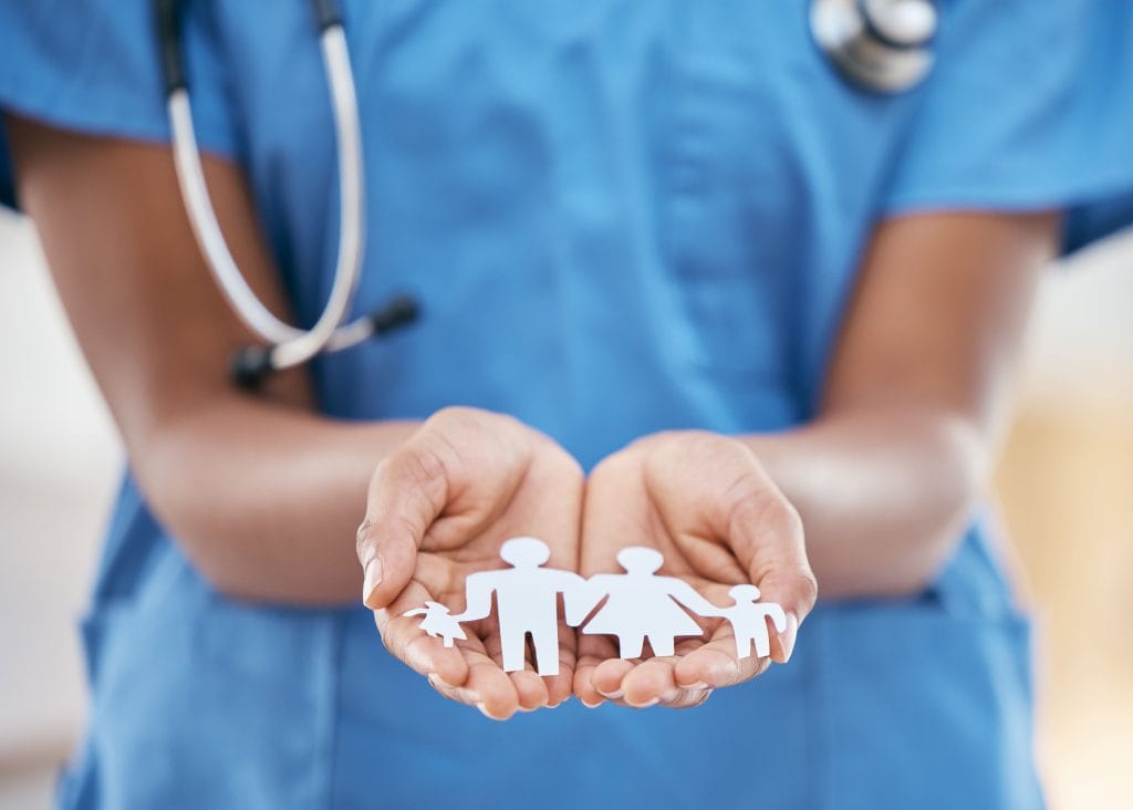 Médecin avec stéthoscope autour du coup qui tient dans sa main un papier découpé en forme de famille
