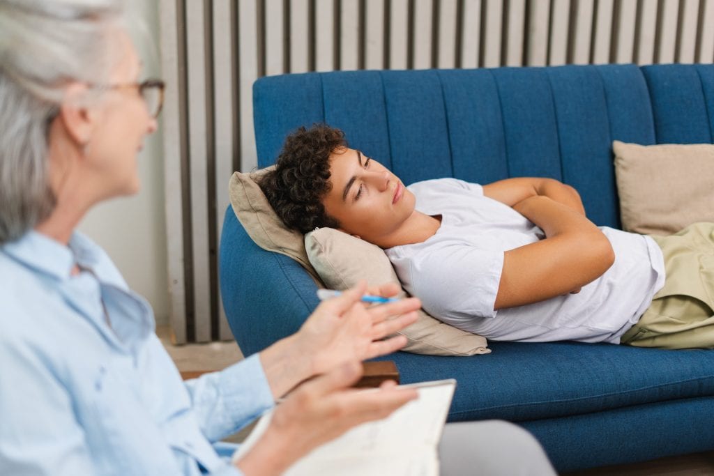 Jeune adolescent allongé sur le divan d'un psychologue.