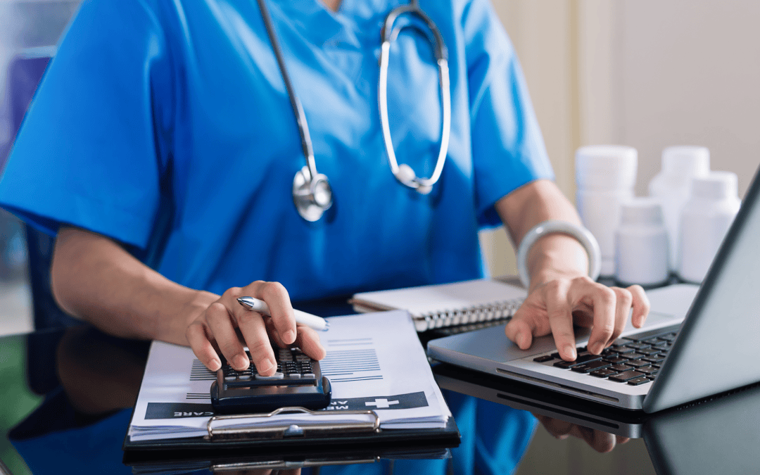 Medecin en blouse bleue utilisant une calculatrice et un ordinateur portable pour calculer et analyser les coûts liés à l’assurance maladie.